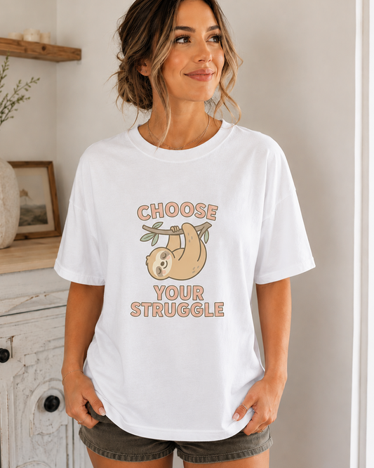 Woman wearing a white t-shirt with a motivational quote that says "choose your struggle" and sloth graphic indoors.