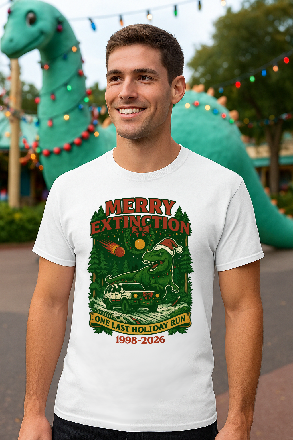 Man wearing a white t-shirt with a graphic t-shirt that has t-rex and is tribute to Dinosaur Ride standing in front of a large inflatable dinosaur.