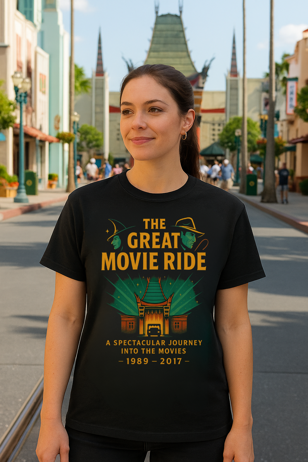Woman wearing a black Gildan 64000 t-shirt featuring The Great Movie Ride tribute design with Chinese Theatre, spotlight rays, and text A Spectacular Journey Into the Movies 1989–2017.