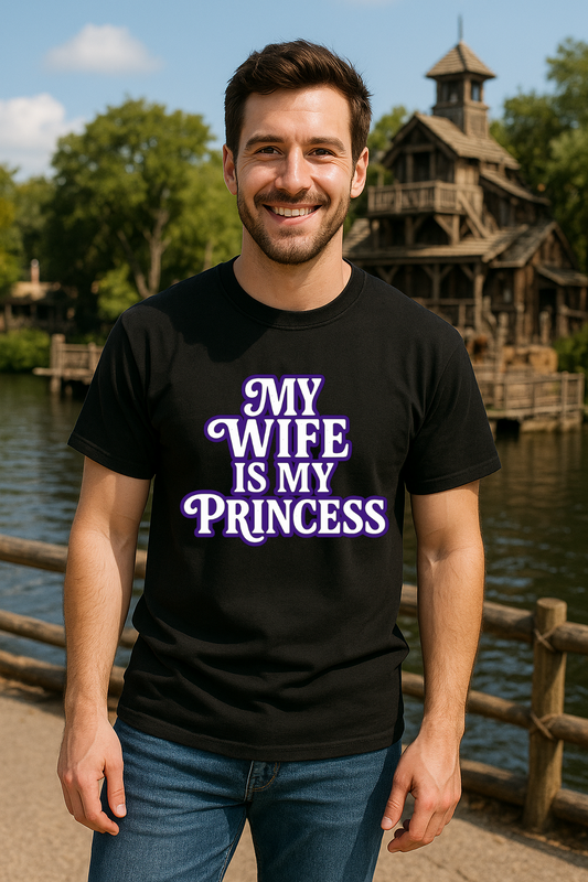 Man wearing a black t-shirt with 'My Wife is My Princess' text, standing outdoors near a body of water and wooden structure.