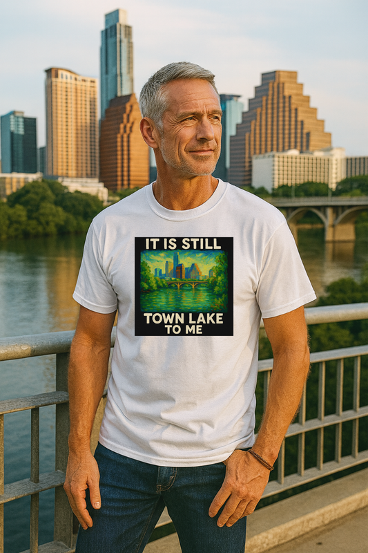 Man wearing a white t-shirt that says "it is still town lake to me" with a standing by a waterfront with a Austin skyline in the background.