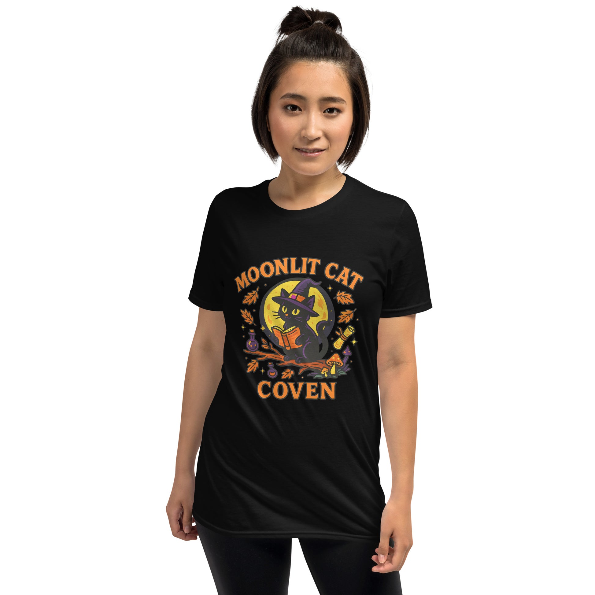 Lady in black graphic t-shirt with the words moonlit cat coven and a cat with a book in front of moon.