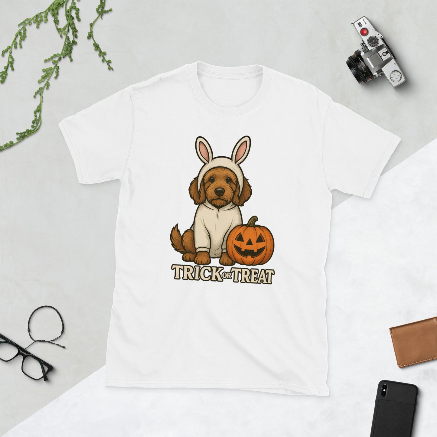 White t-shirt with a golden doodle dog in a bunny costume and pumpkin graphic, labeled 'Trick or Treat', on a light gray background.