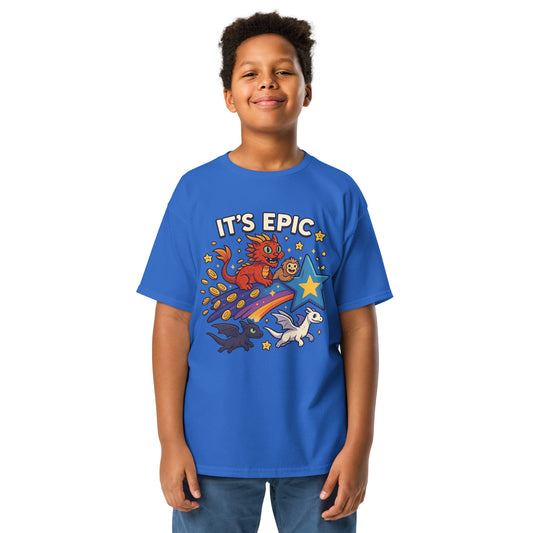Smiling boy wearing a blue Gildan youth t-shirt with colorful “It’s EPIC” design featuring a red cat-dragon, monkey, comet, coins, stars, and two dragons.