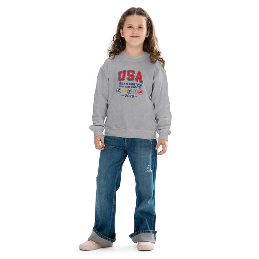 Girl in blue jeans and a gray sweatshirt that says USA and Milan Cortina Winter Games.